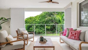 A room with a balcony, white furniture, and a ceiling fan. - A Calm City Base Cairns CBD (Cairns North)