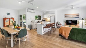 Una cocina moderna con armarios blancos, una isla central y taburetes de bar.