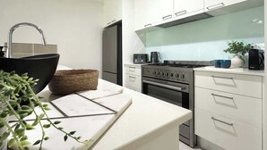 Une cuisine moderne avec des meubles blancs, un évier noir et une cuisinière.