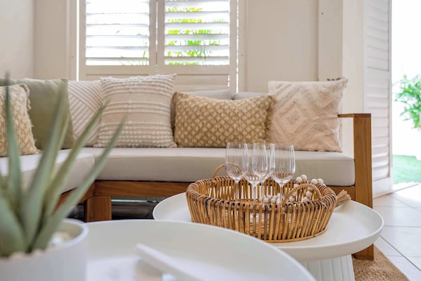 A room with a sofa, a wicker basket with glasses, and a potted plant. - Spacious Retreat with Courtyard & Resort Pool (Cairns North)