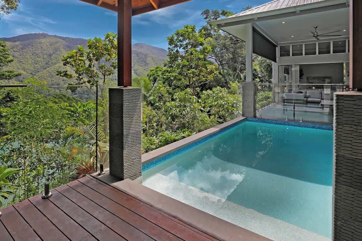Ein Pool mit Bergblick, einer überdachten Sitzgelegenheit und einer Holzterrasse.