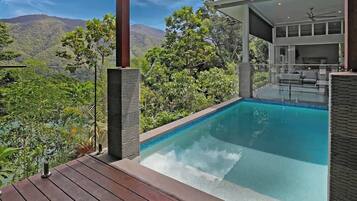Ein Pool mit Bergblick, einer überdachten Sitzgelegenheit und einer Holzterrasse.
