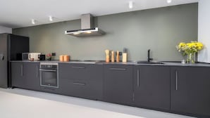 A modern kitchen with dark cabinetry, a built-in oven, a microwave, and a stainless steel range hood.