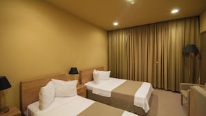 A hotel room with two beds, a desk, a chair, and a large window with curtains. - Hotel Anaklia  (Anaklia)