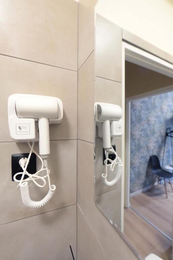 Ein Badezimmer mit zwei Haartrocknern an der Wand und einem Spiegel.