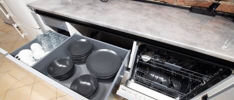 Una cocina con lavavajillas integrado, pared de ladrillo y encimera con un tostador.