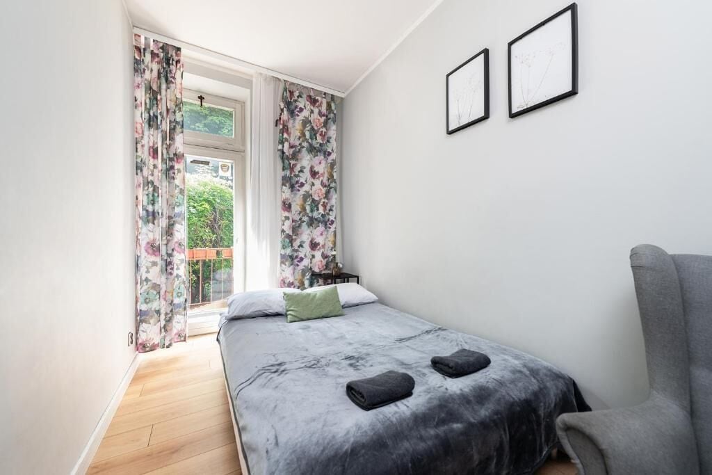 Un dormitorio con cama, dos cuadros en la pared y una ventana con cortinas.