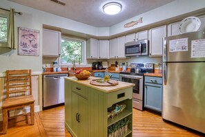 Una cocina con isla de madera, electrodomésticos de acero inoxidable y una ventana con vistas a zonas verdes.