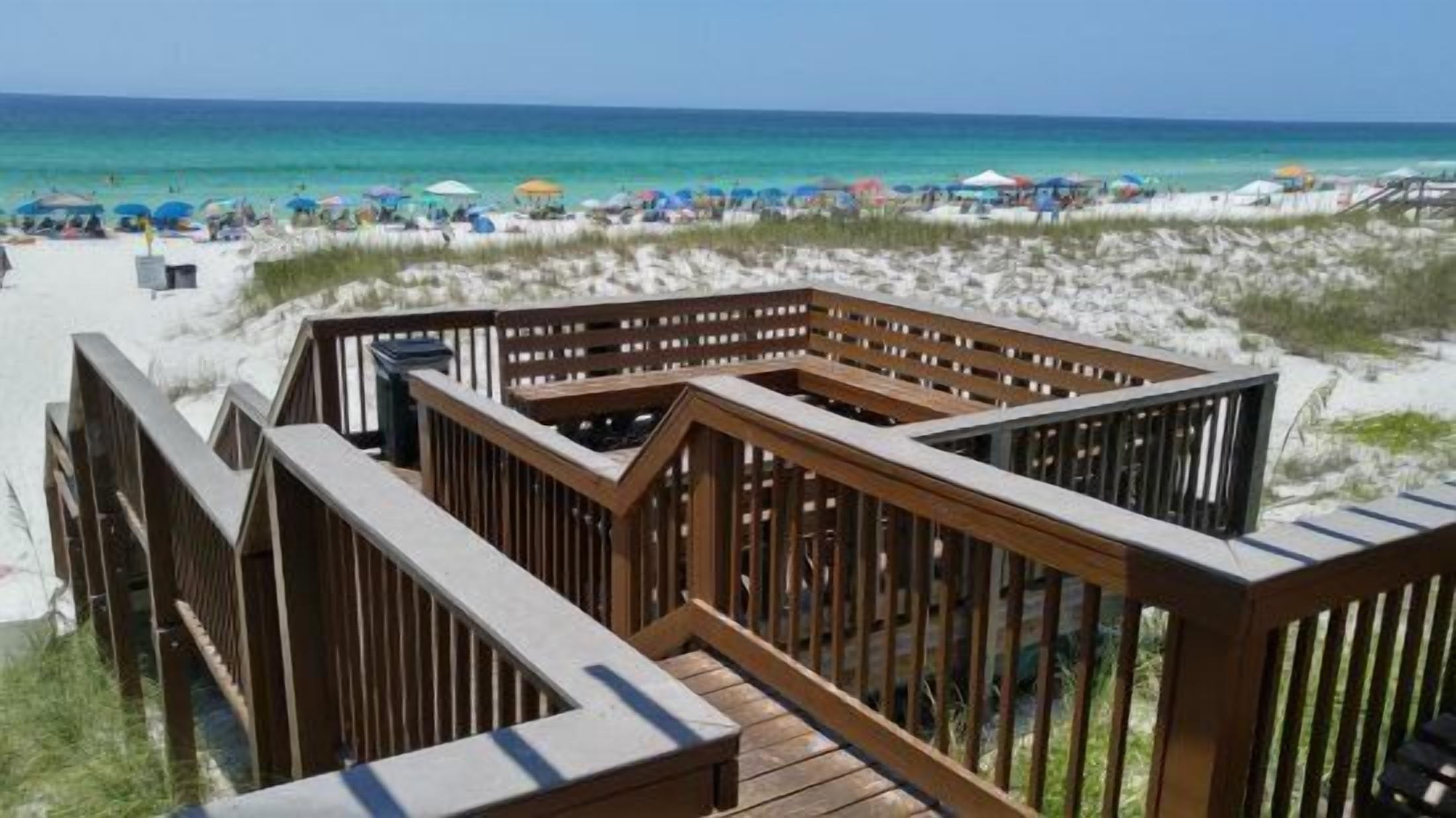 A wooden deck with a view of the beach and ocean.