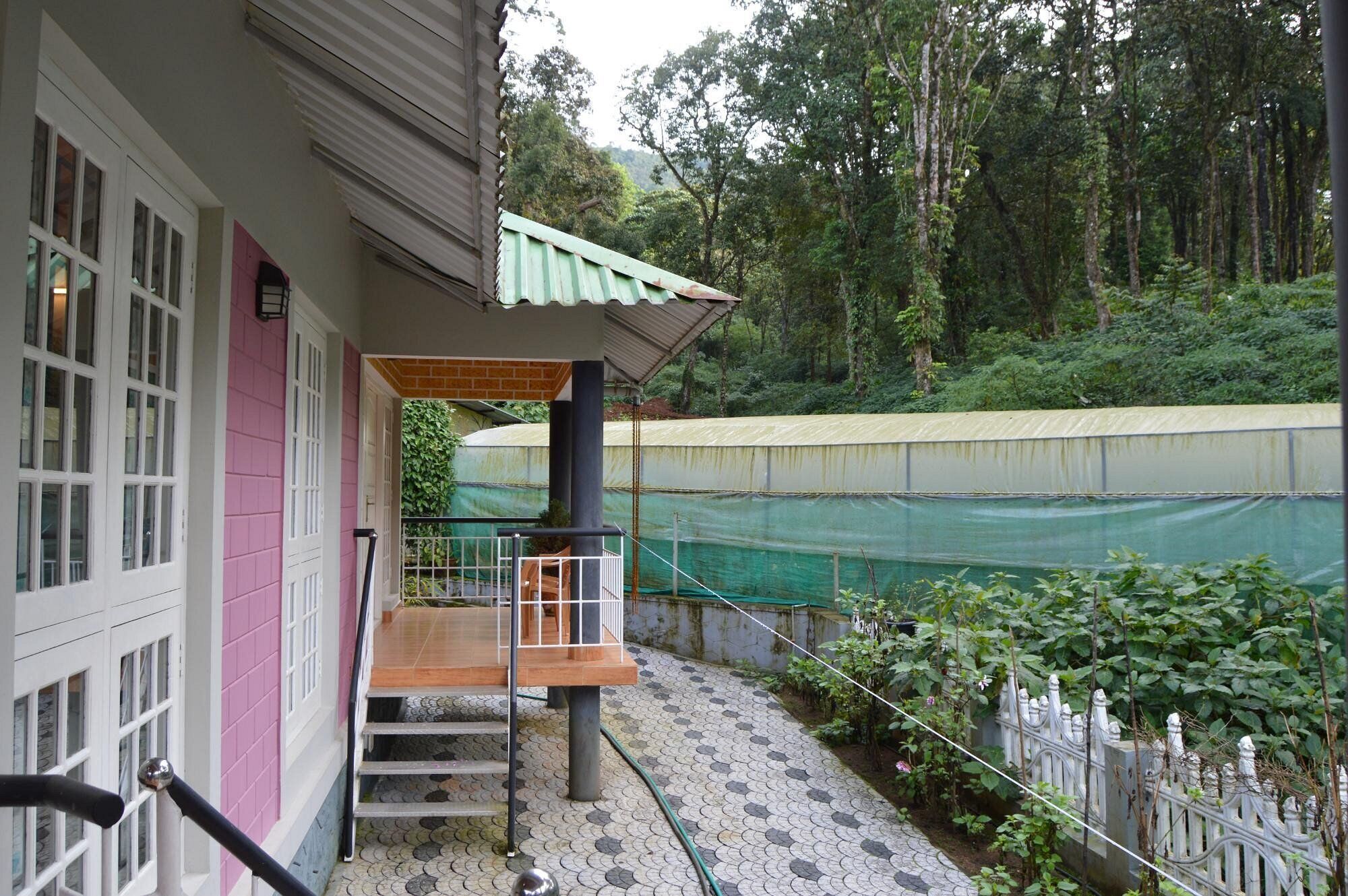 Un edificio con un espacio exterior cubierto, una escalera y vista a un área boscosa.