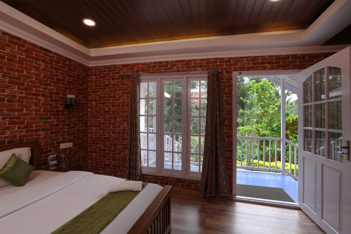 Una habitación con pared de ladrillo, ventana grande, balcón y cama.