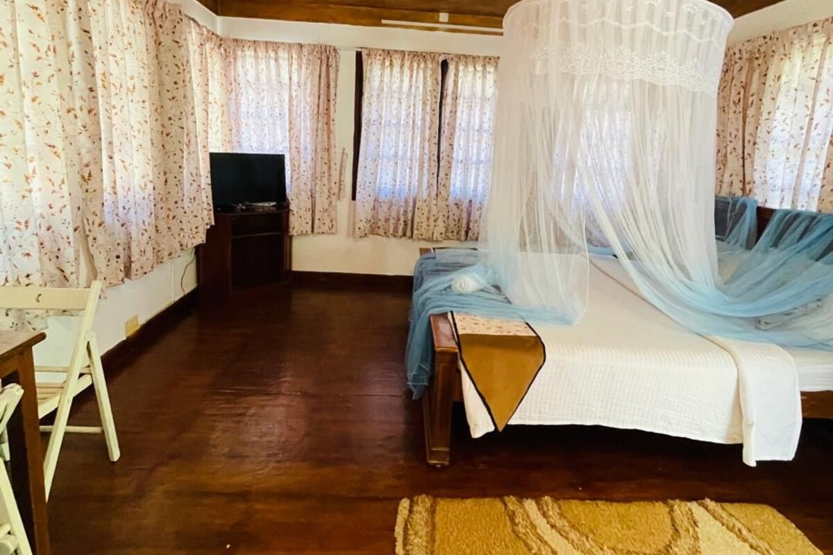 A room with a bed, a television, and a wooden ceiling.
