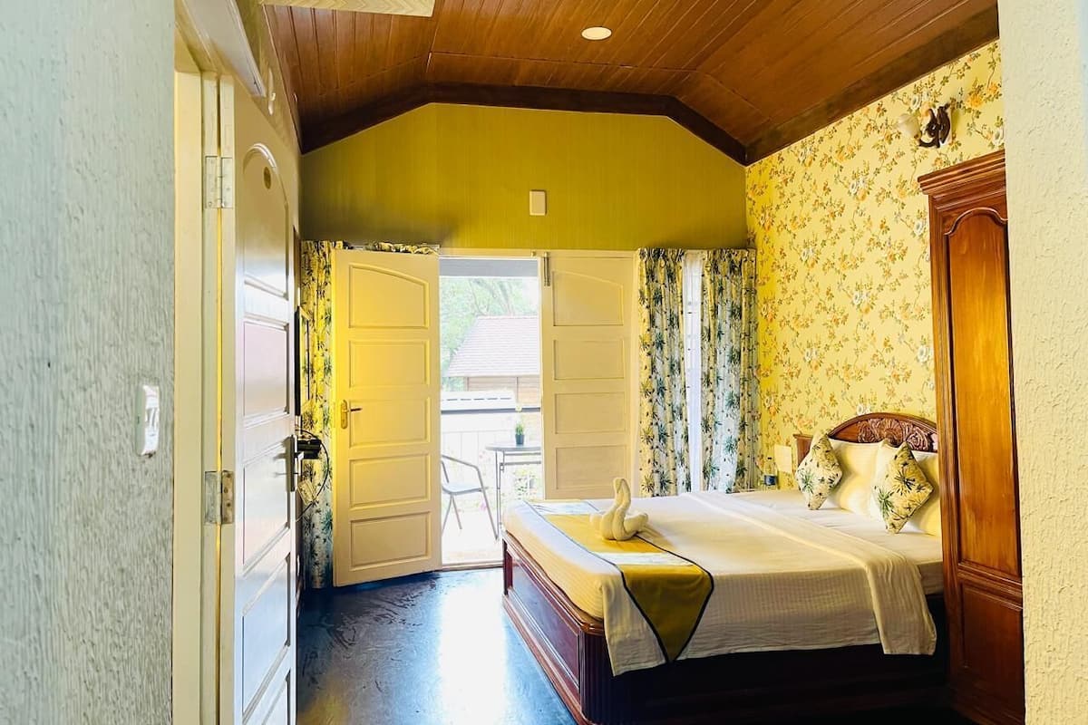 Un dormitorio con cama, techo de madera, una puerta y vistas al exterior.