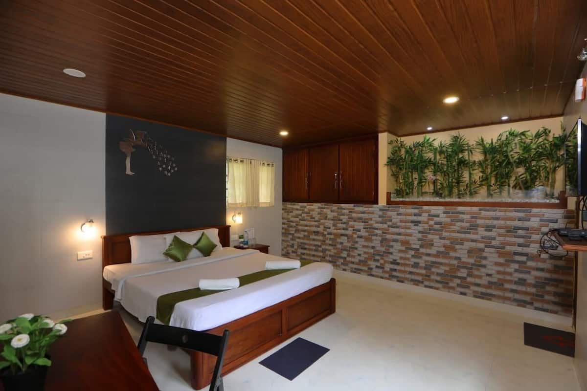 Habitación de hotel con una cama grande, techo de madera, pared de ladrillo y un televisor sobre un escritorio.