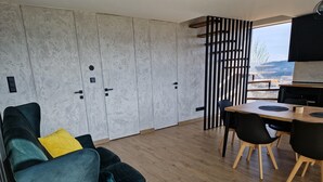 A modern living room with a sofa, a dining table with chairs, and a view through a window. - House With a Garden and a View of the Mountains (Makow Podhalanski)