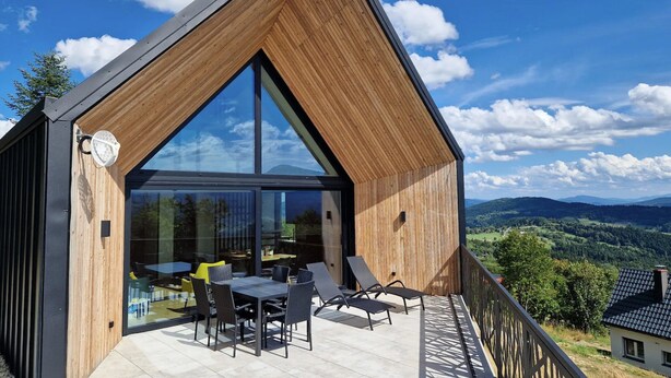 A modern house with a large glass window, a wooden exterior, and a balcony overlooking a scenic landscape. - House With a Garden and a View of the Mountains (Makow Podhalanski)