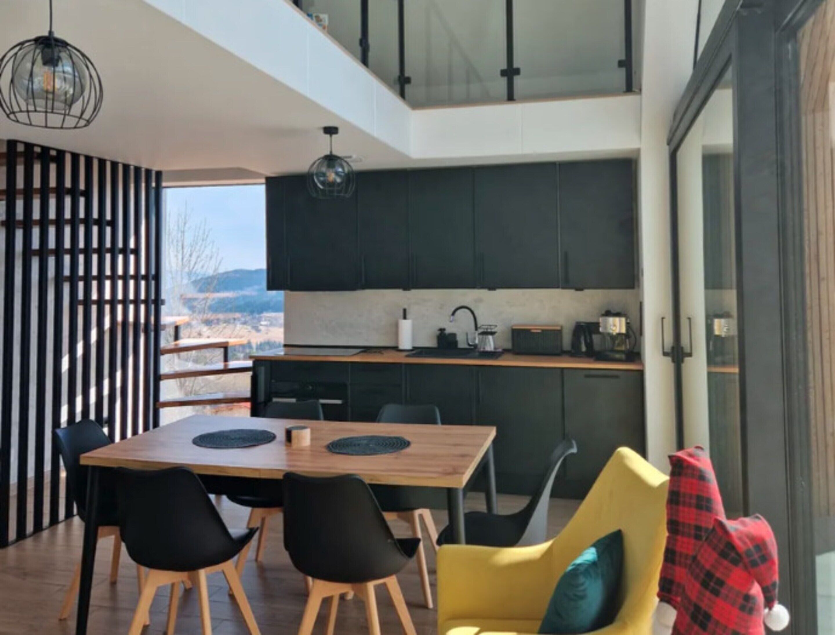 A modern kitchen with dark cabinets, a wooden countertop, and a view of the outdoors.
