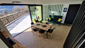 A modern interior with a dining area, a sofa, and a view through a large window. - House With a Garden and a View of the Mountains (Makow Podhalanski)