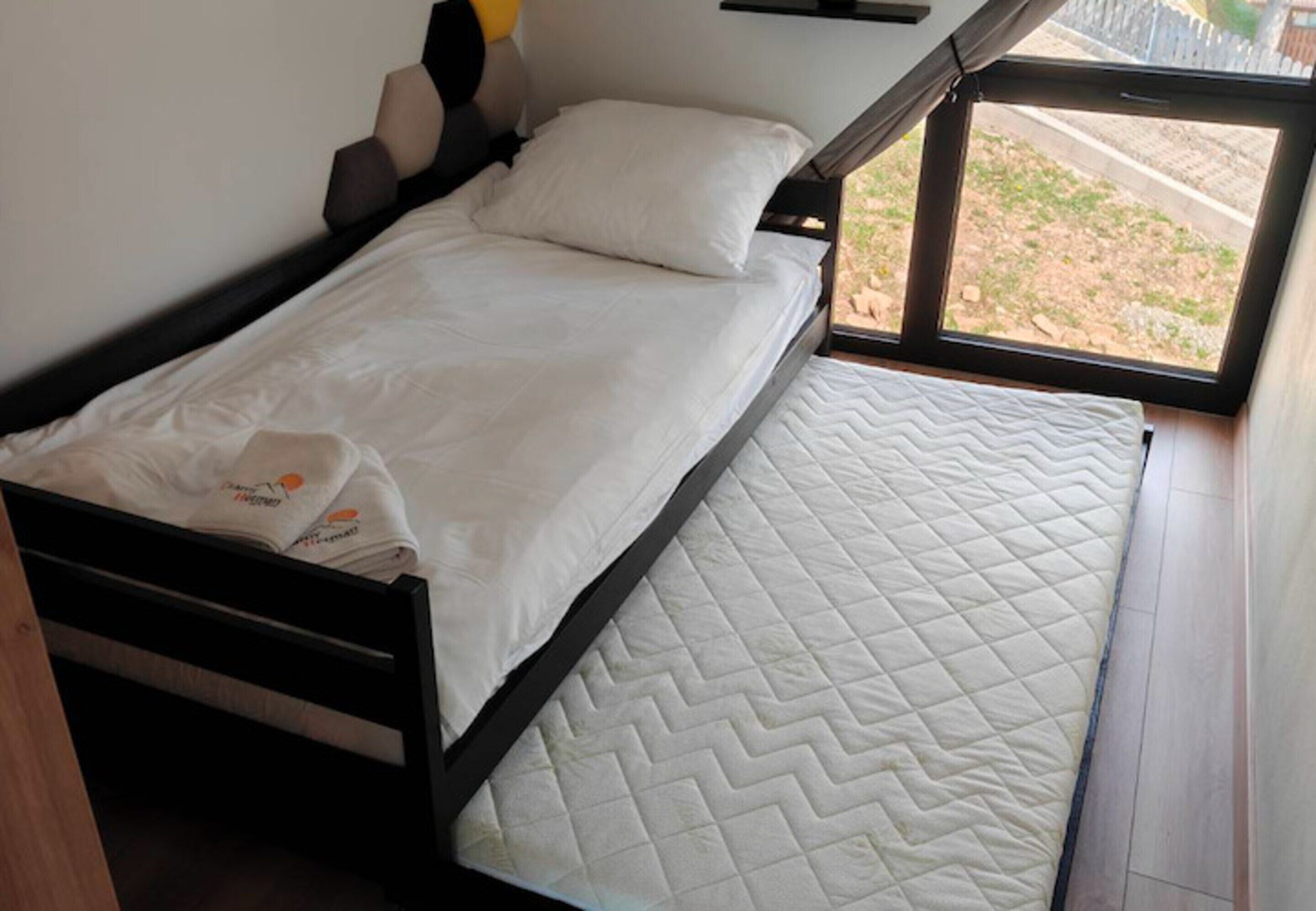 A single bed with a quilted mattress, a pillow, and a headboard.