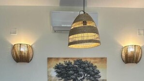 A dining area with a wooden table, four chairs, a vase with flowers, and wall-mounted lighting fixtures. - Scandal House by All About Paxos (Paxos)