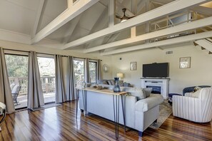 A spacious living area with a high ceiling, a fireplace, a television, and a balcony with outdoor seating. - Updated Luxury 3 BR Queens Grant lagoon view Bikes & Beach gear included (Hilton Head Island)