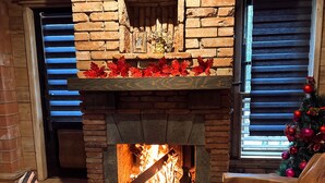 A fireplace with a brick surround, a bench, and a Christmas tree.