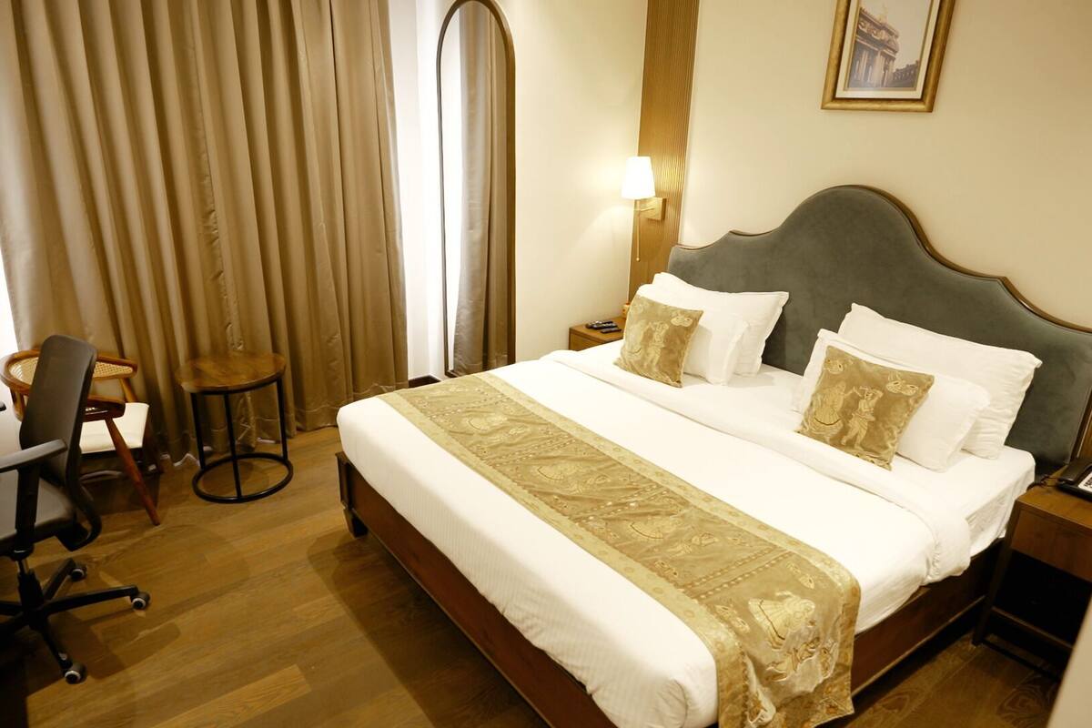 Una habitación de hotel con cama, escritorio, silla y lámpara.