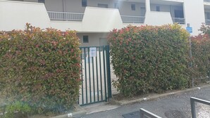 A multi-story building with balconies, a gated entrance, and dense foliage. - T2 cabin with terrace, close to beach and port, all amenities on foot (Saint-Cyprien)