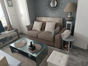 A living room with a sofa, coffee table, and ottoman. - T2 cabin with terrace, close to beach and port, all amenities on foot (Saint-Cyprien)