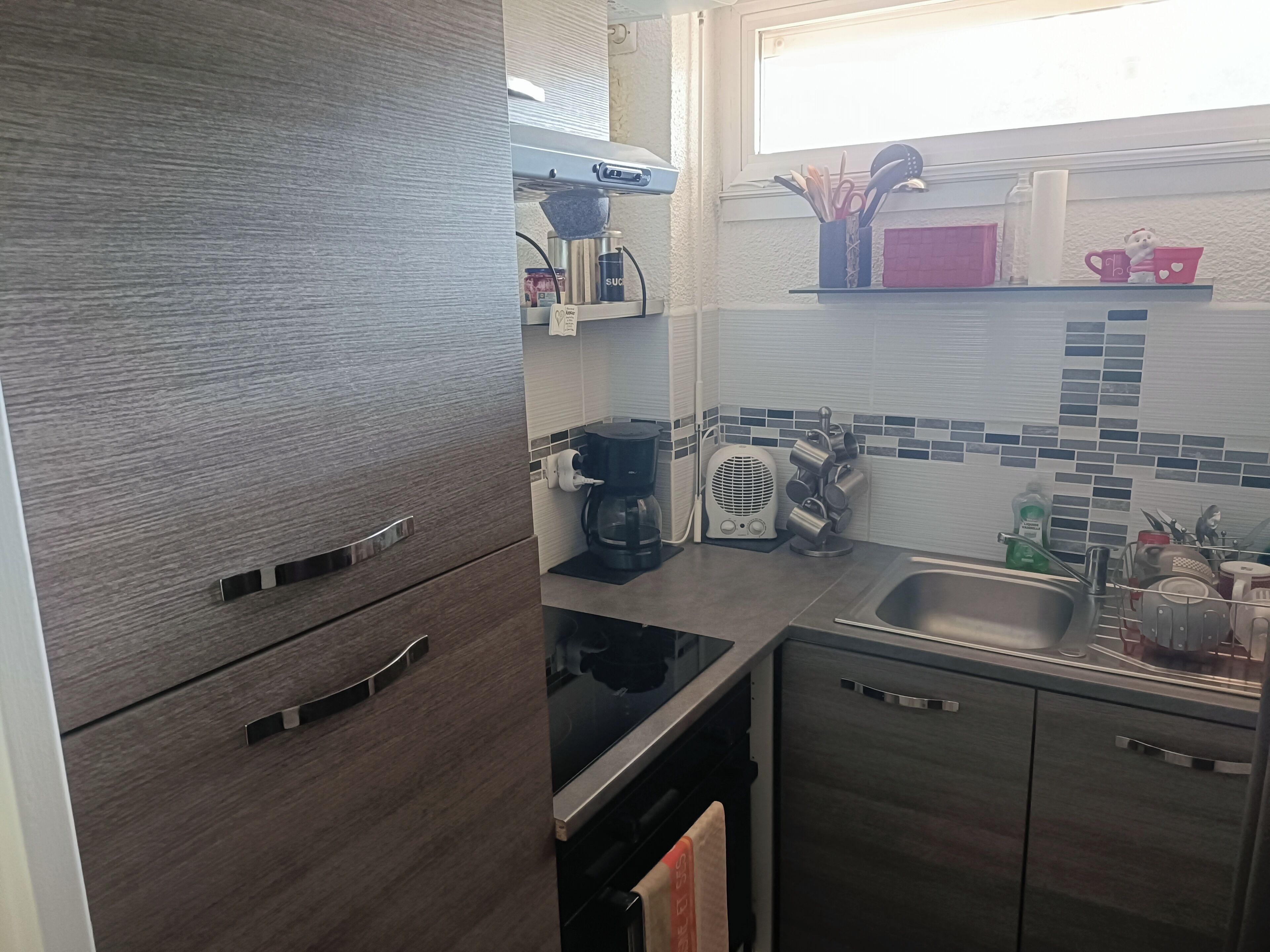A modern kitchen with a built-in oven, a coffee maker, and a sink.