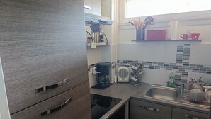 A modern kitchen with a built-in oven, a coffee maker, and a sink. - T2 cabin with terrace, close to beach and port, all amenities on foot (Saint-Cyprien)