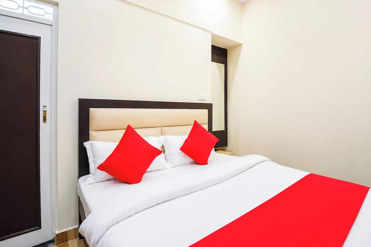A hotel room with a bed, a door, and a mirror on the wall.