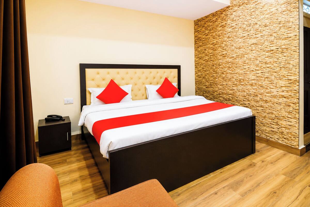 A hotel room with a bed, a nightstand, a wooden floor, and a textured wall.