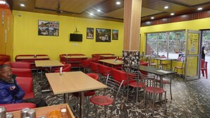 Interior de restaurante con paredes amarillas, sillas rojas y mesas.