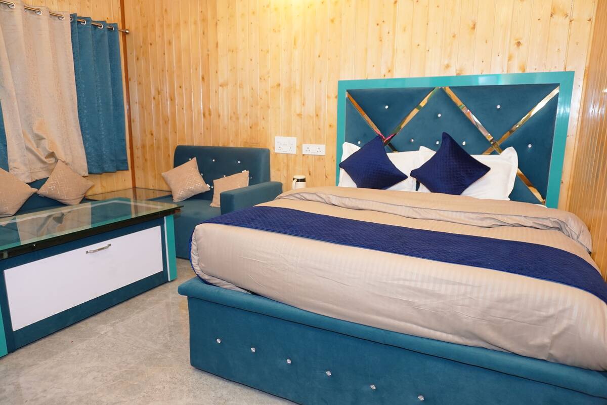 Un dormitorio con una cama, una mesita de cristal, una silla y paneles de madera.
