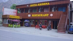 Un edificio de dos pisos con un letrero que dice 'Hotel Krishna Restaurant'.