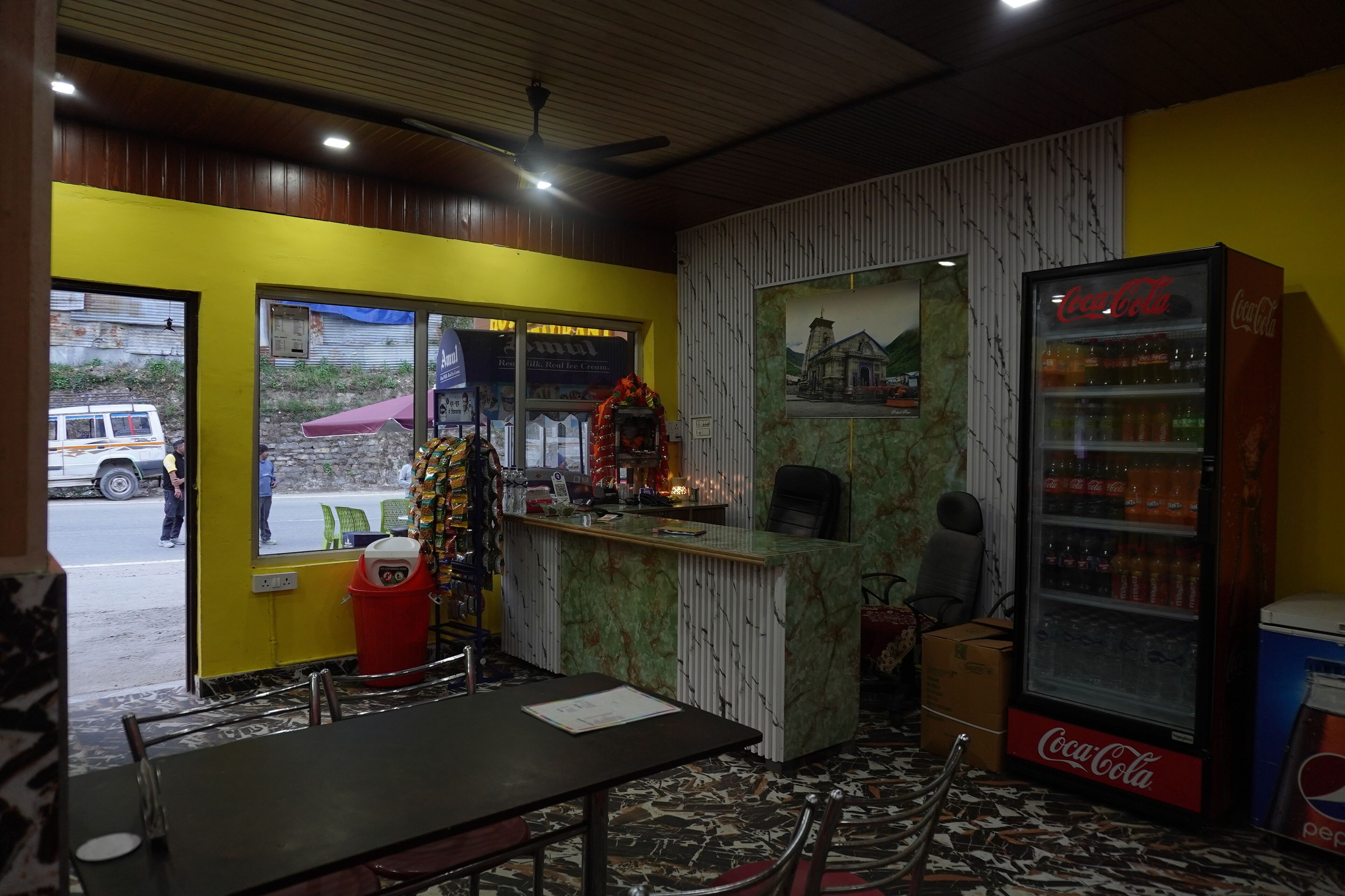 A restaurant with a counter, seating area, and a Coca-Cola refrigerator.