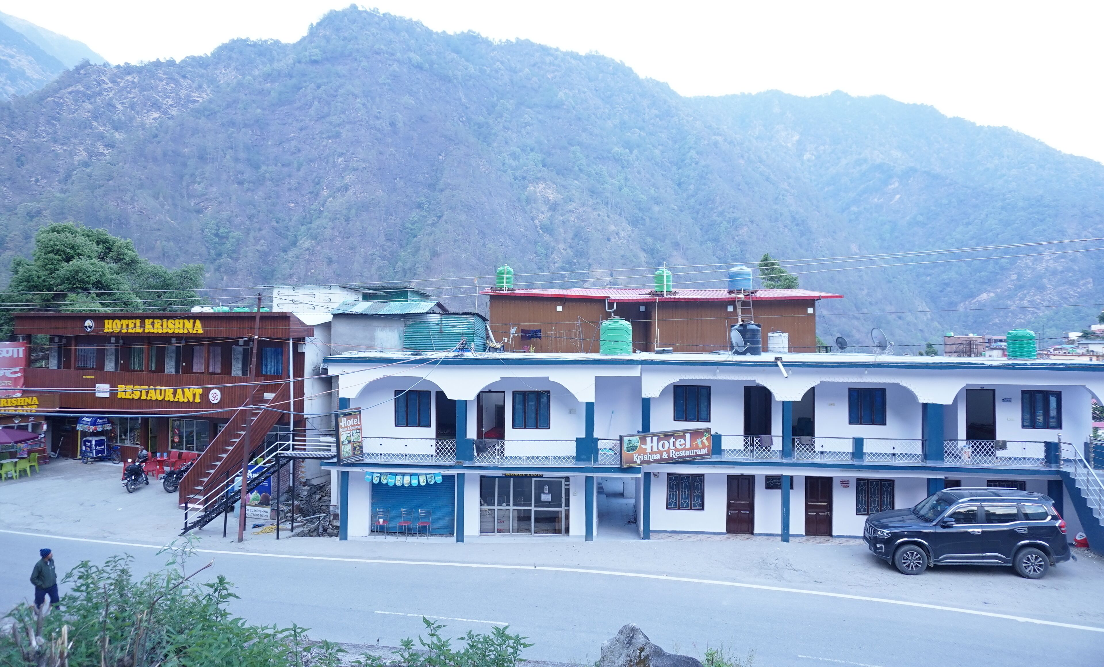 A hotel with a signboard, a staircase, and a parked car.