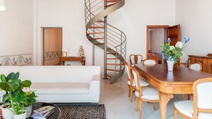 Een modern interieur met een spiltrap, een eetgedeelte met houten meubels en een witte bank.