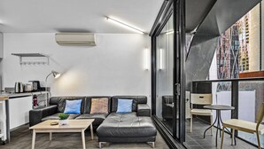 A modern living space with a sofa, coffee table, and a dining area with chairs. - Central 2 Bed Apartment Near Melbourne CBD (Melbourne)