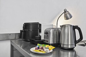 A kitchenette with a coffee maker, toaster, kettle, and a plate with food items. - Central 2 Bed Apartment Near Melbourne CBD (Melbourne)