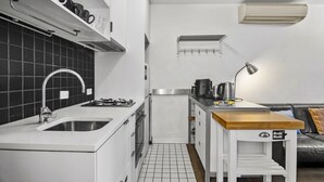 A compact kitchen with a sink, stove, and a small wooden table. - Central 2 Bed Apartment Near Melbourne CBD (Melbourne)
