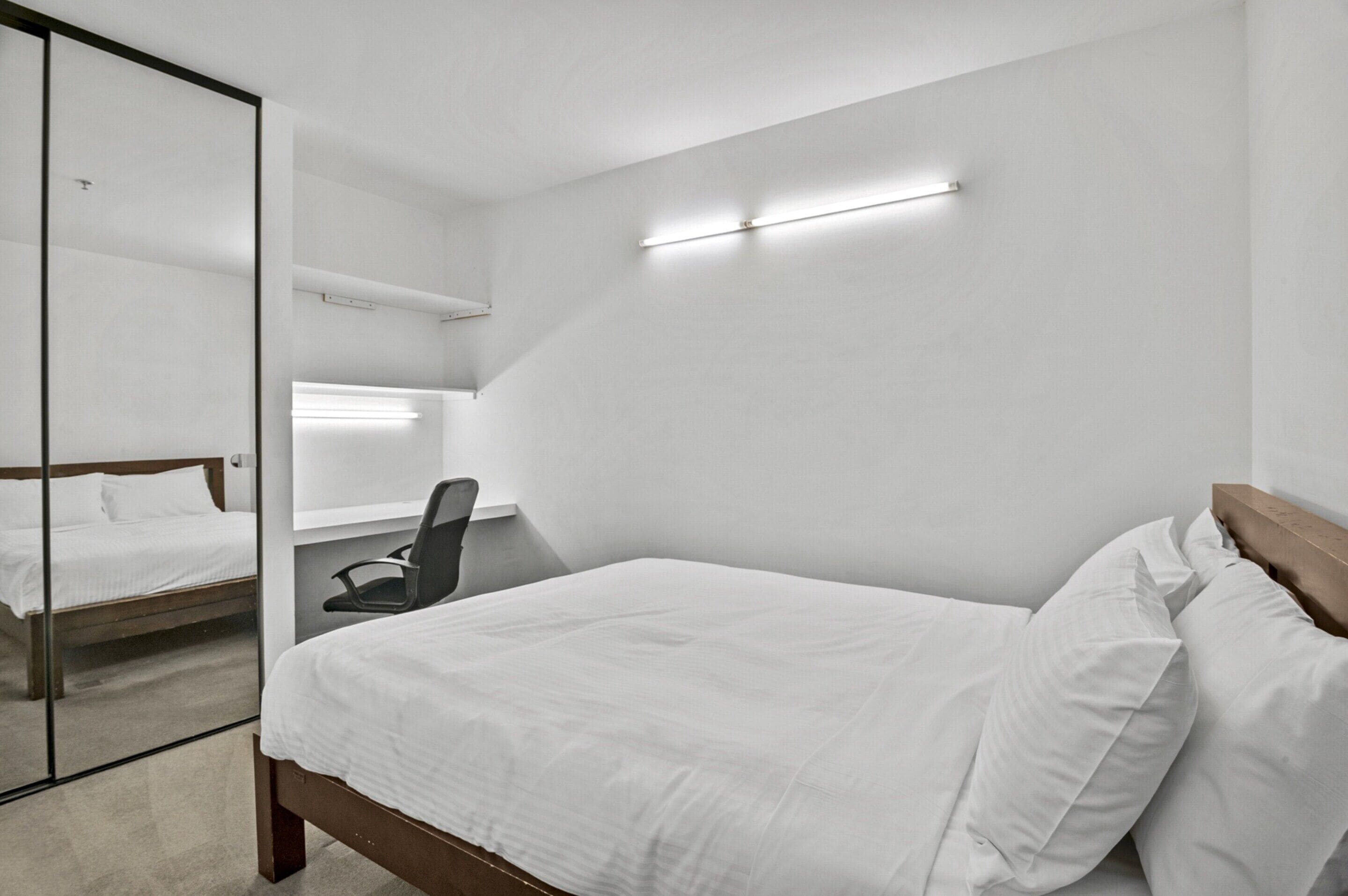 Quarto de hotel moderno com uma cama grande, uma mesa e um espelho.