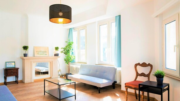 Un salon avec un canapé, une table, une chaise, une cheminée et une fenêtre avec des rideaux.