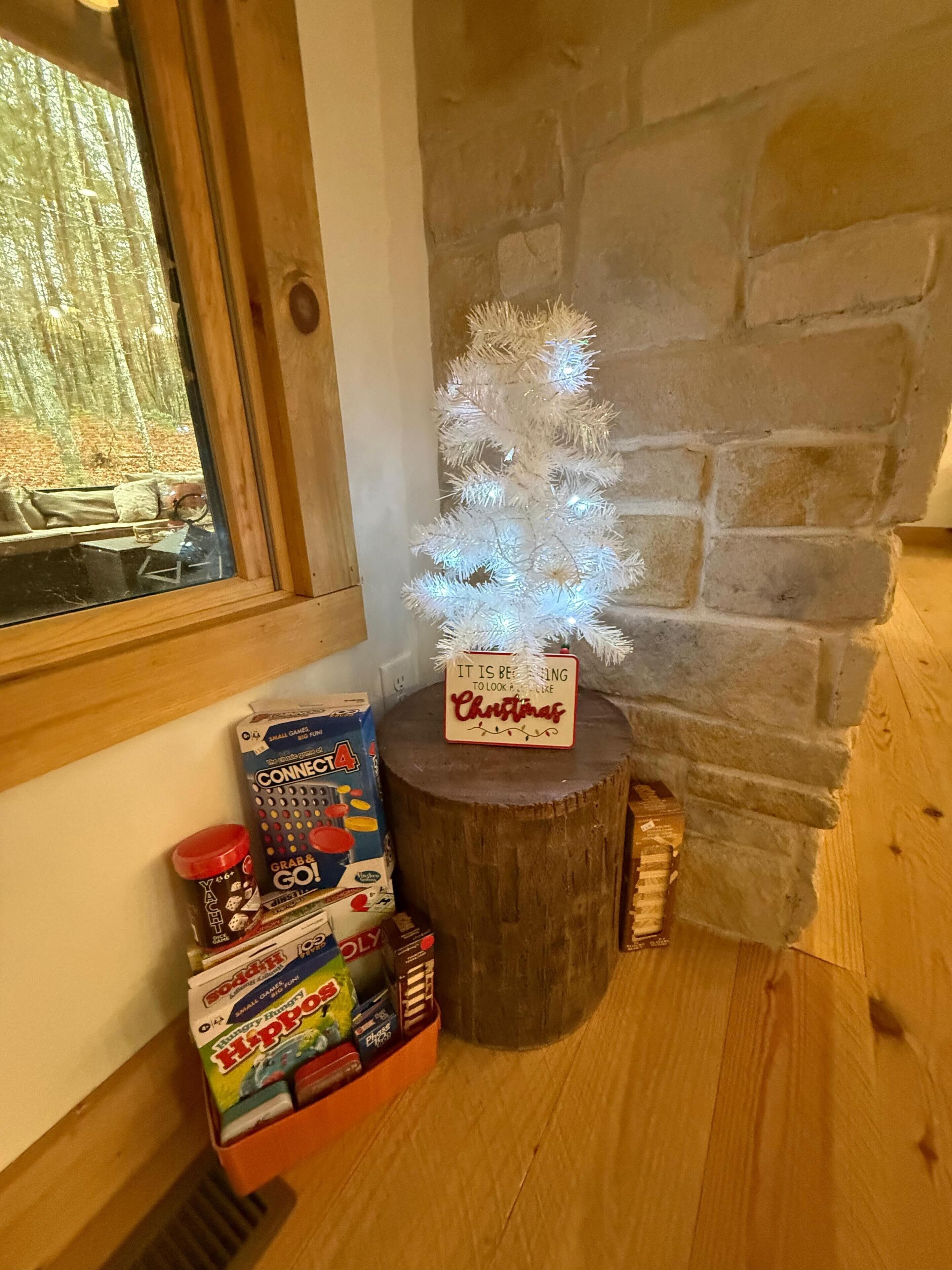 A wooden table with a Christmas tree, a sign, and board games.