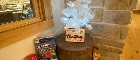A wooden table with a Christmas tree, a sign, and board games.