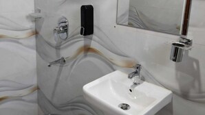 Ein Badezimmer mit Marmorwand, Waschbecken, Spiegel, einer Seifenspender und einem Eimer.