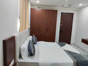 A bedroom with a bed, two wardrobes, a ceiling fan, and a nightstand. - Hotel Skyva (Hyderabad)