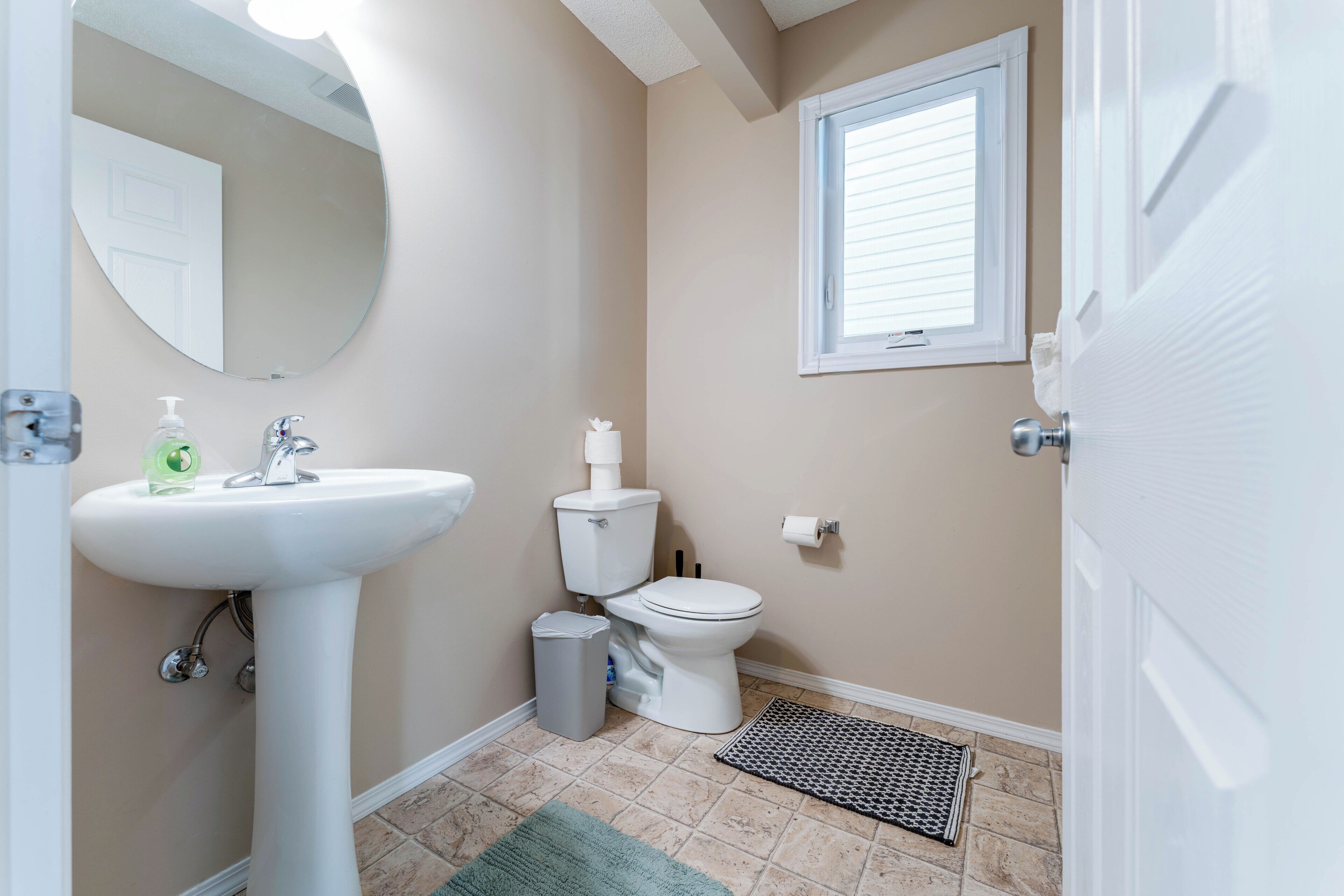 A bathroom with a sink, toilet, and window.