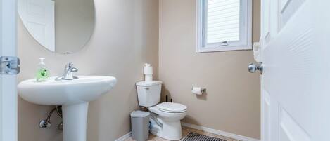 A bathroom with a sink, toilet, and window.